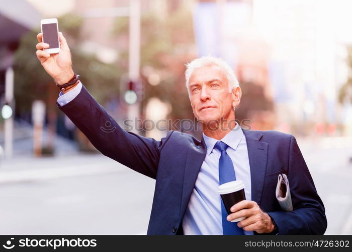 Businessman catching taxi in city. Businessman in suit catching taxi in city with cup of coffee in his hands