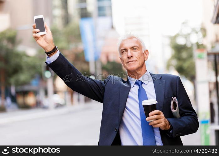 Businessman catching taxi in city. Businessman in suit catching taxi in city with cup of coffee in his hands