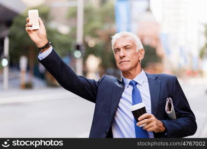 Businessman catching taxi in city. Businessman in suit catching taxi in city with cup of coffee in his hands