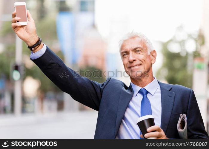 Businessman catching taxi in city. Businessman in suit catching taxi in city with cup of coffee in his hands