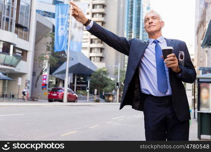 Businessman catching taxi in city. Businessman in suit catching taxi in city with cup of coffee in his hands