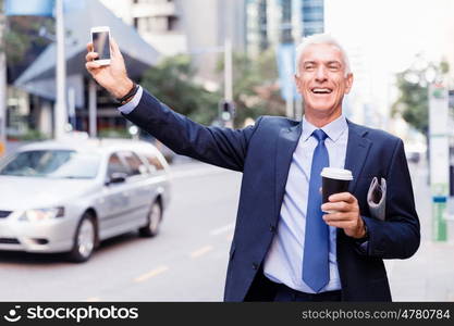 Businessman catching taxi in city. Businessman in suit catching taxi in city with cup of coffee in his hands