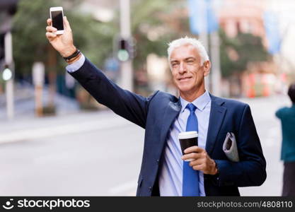 Businessman catching taxi in city. Businessman in suit catching taxi in city with cup of coffee in his hands