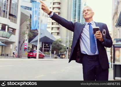 Businessman catching taxi in city. Businessman in suit catching taxi in city with cup of coffee in his hands