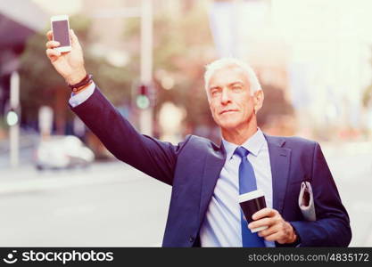 Businessman catching taxi in city. Businessman in suit catching taxi in city with cup of coffee in his hands