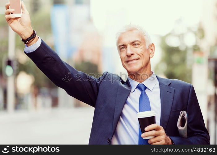 Businessman catching taxi in city. Businessman in suit catching taxi in city with cup of coffee in his hands