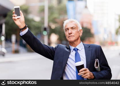 Businessman catching taxi in city. Businessman in suit catching taxi in city with cup of coffee in his hands