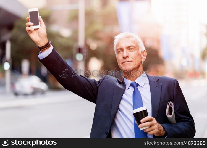 Businessman catching taxi in city. Businessman in suit catching taxi in city with cup of coffee in his hands