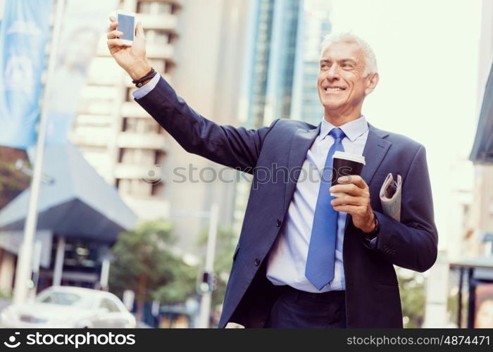 Businessman catching taxi in city. Businessman in suit catching taxi in city with cup of coffee in his hands