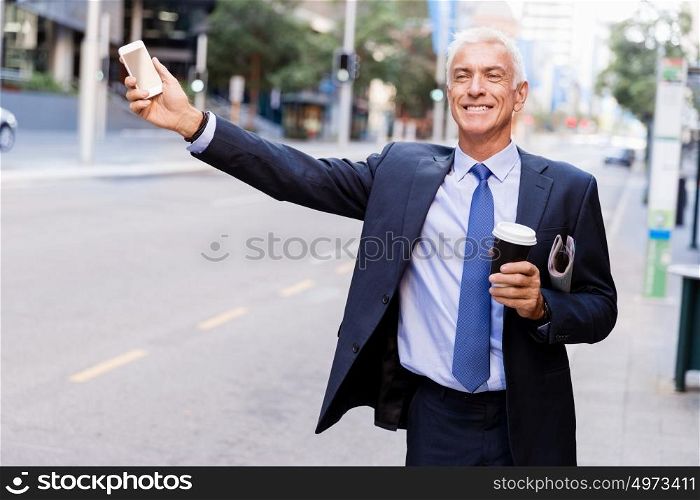 Businessman catching taxi in city. Businessman in suit catching taxi in city with cup of coffee in his hands