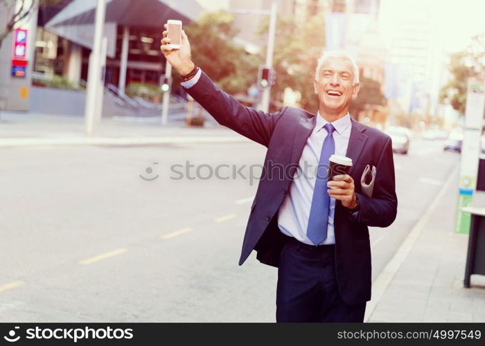 Businessman catching taxi in city. Businessman in suit catching taxi in city with cup of coffee in his hands