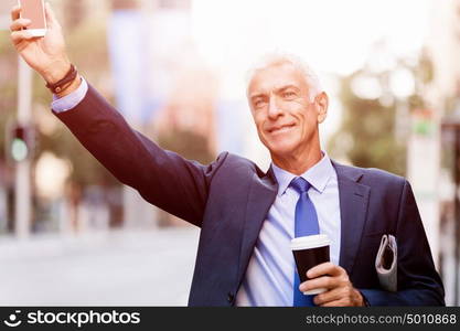 Businessman catching taxi in city. Businessman in suit catching taxi in city with cup of coffee in his hands