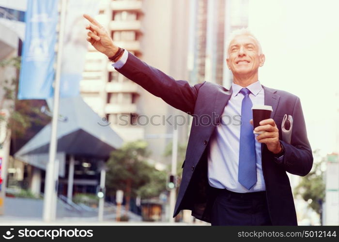 Businessman catching taxi in city. Businessman in suit catching taxi in city with cup of coffee in his hands