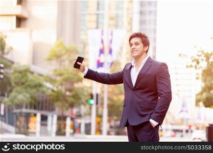 Businessman catching taxi in city. Businessman in suit catching taxi in city with mobile phone in his hands