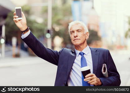 Businessman catching taxi in city. Businessman in suit catching taxi in city with cup of coffee in his hands