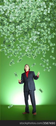 businessman catchs flying banknotes on green background