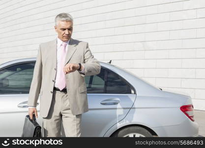 Businessman checking the time in front of car outdoors