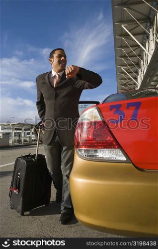 Businessman checking the time near a taxi outside an airport