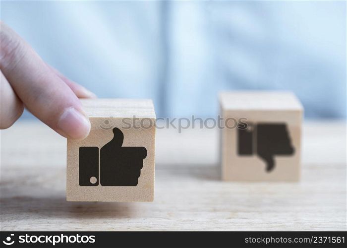 Businessman chooses a emoticon icons approval in social networks and rating like symbol on wooden block
