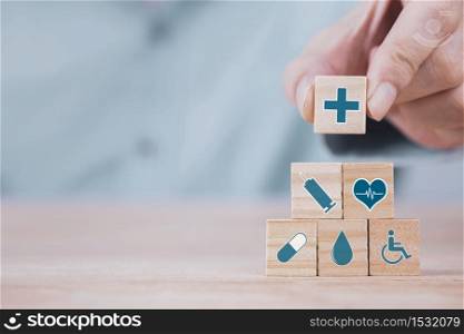 Businessman chooses a emoticon icons healthcare medical symbol on wooden block , Healthcare and medical Insurance concept