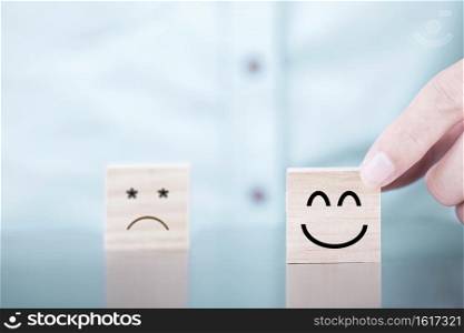 Businessman chooses a smile emoticon icons face happy symbol on wooden block , Services and Customer satisfaction survey concept