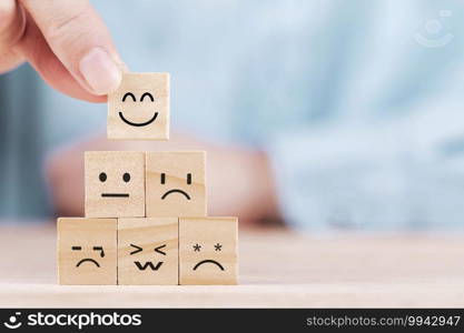 Businessman chooses a smile emoticon icons face happy symbol on wooden block , Services and Customer satisfaction survey concept