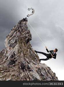 businessman climbing mountain with question sigh on top