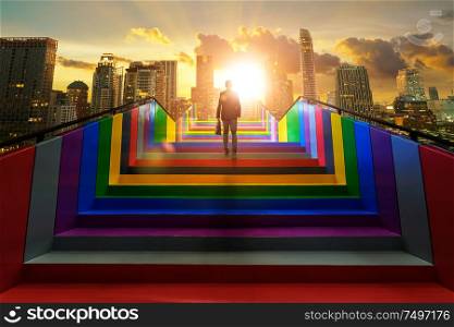 Businessman climbing on colorful stair to modern city, ambitions concept .