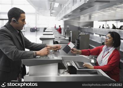 Businessman collecting his passport with an airplane ticket from the airline check-in attendant