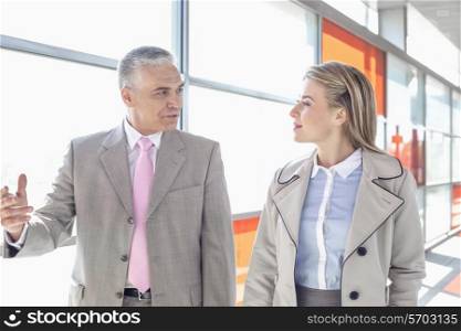 Businessman communicating with female colleague while walking in railroad station