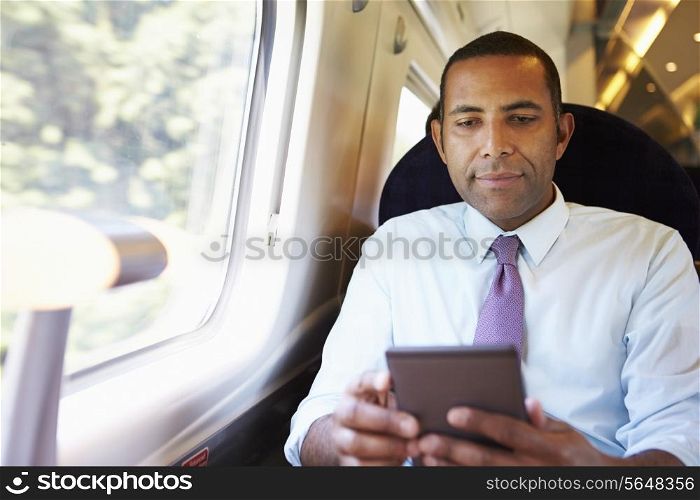 Businessman Commuting On Train Reading E Book
