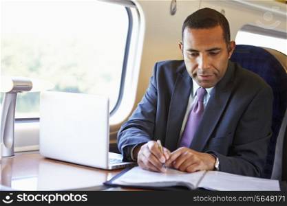 Businessman Commuting To Work On Train And Using Laptop