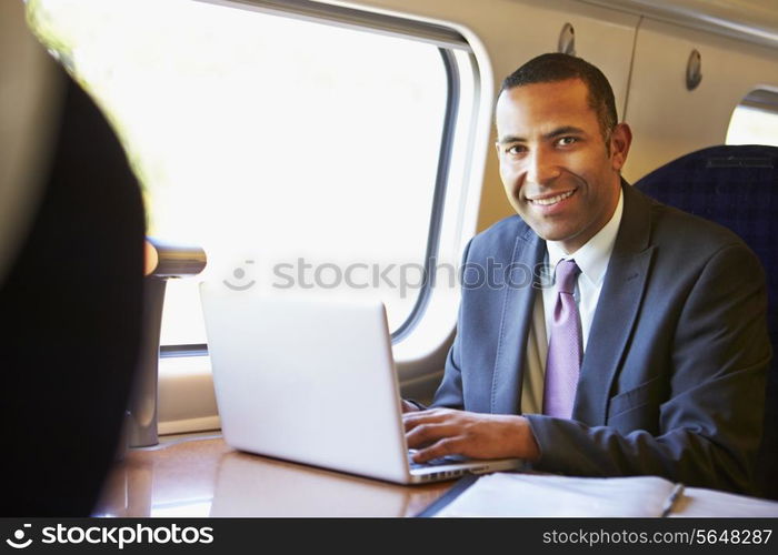 Businessman Commuting To Work On Train And Using Laptop