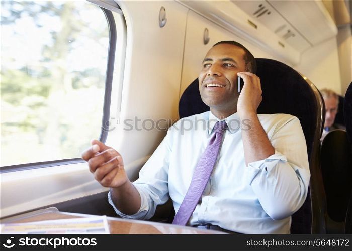 Businessman Commuting To Work On Train Using Mobile Phone