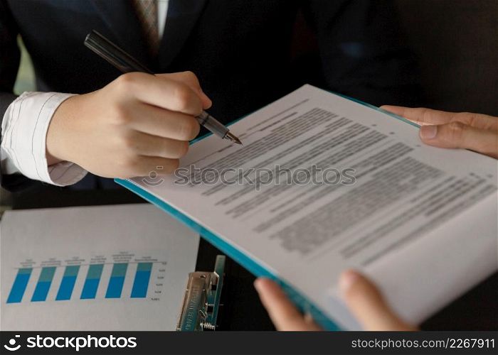 Businessman concept the marketing analyst checking the data on the paper to compare with the information in the graphic for analysis.