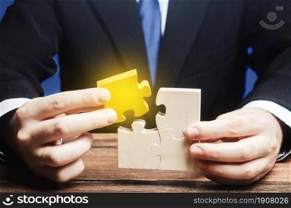 Businessman connects a golden part to puzzle assembly. Creating new product, Innovation development. Stakeholder management. Project completion. Find a solution. Right choice. Achieving Success