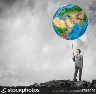 Businessman controlling Earth planet with lead. Elements of this image are furnished by NASA. World is mine
