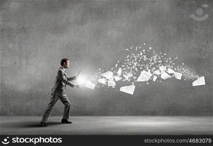 Businessman controlling paper documents flying in air. Everything is under control