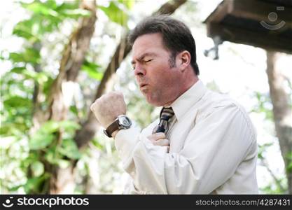 Businessman coughing from the flu, a cold, or other illness, in outdoor environment.