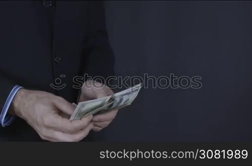 Businessman counts money in hands. Dollars