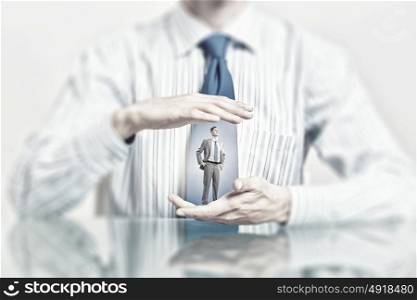 Businessman covered with palms. Miniature of businessman in palm protected with care