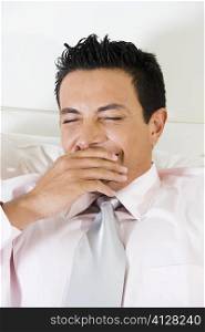 Businessman covering his mouth with his hand while yawning