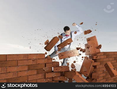 Businessman crashing bricks. Determined businessman breaking stone bricks with hand punch