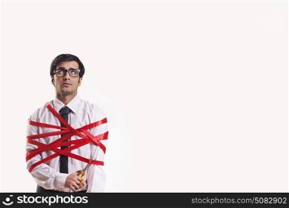 Businessman cutting his wrapped red ribbon