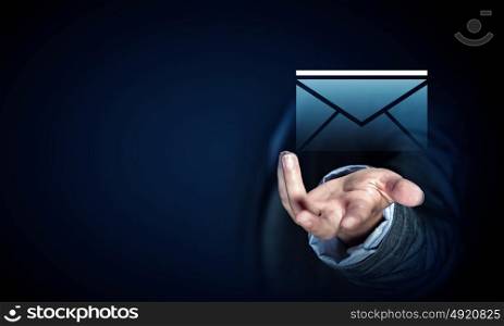 Businessman demonstrating email concept. Close up of businessman palm holding email icon on dark background