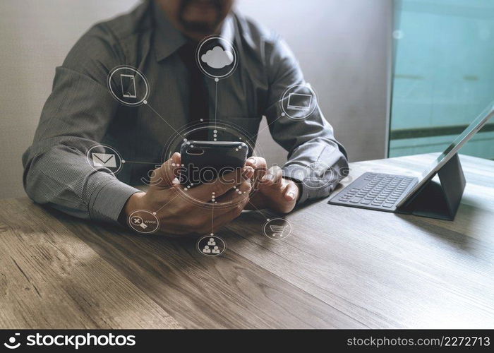 businessman Designer hand using mobile payments online shopping,omni channel,in modern office wooden desk,icons graphic interface screen