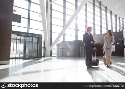 Businessman discussing plans with businesswoman in airport