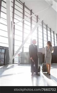 Businessman discussing plans with businesswoman in airport