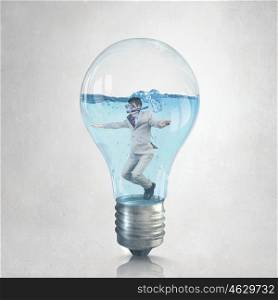 Businessman diver. Young businessman in suit and diving mask swiming in lightbulb with water