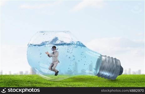 Businessman diver. Young businessman in suit and diving mask swiming in lightbulb with water